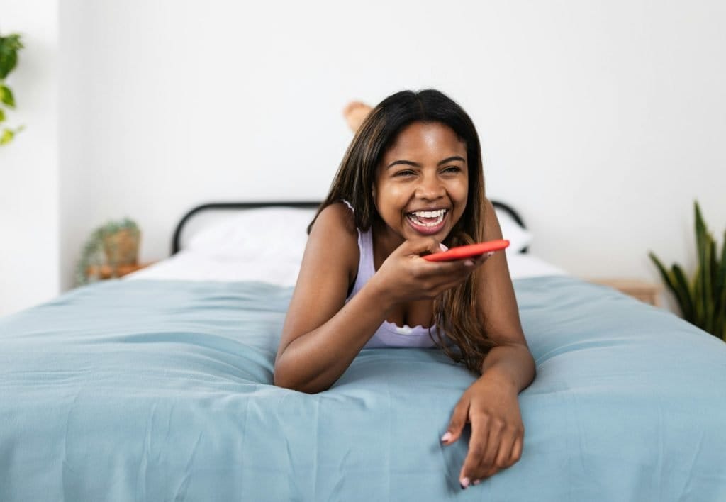 Smiling hispanic latin young woman sending voice audio message on mobile phone